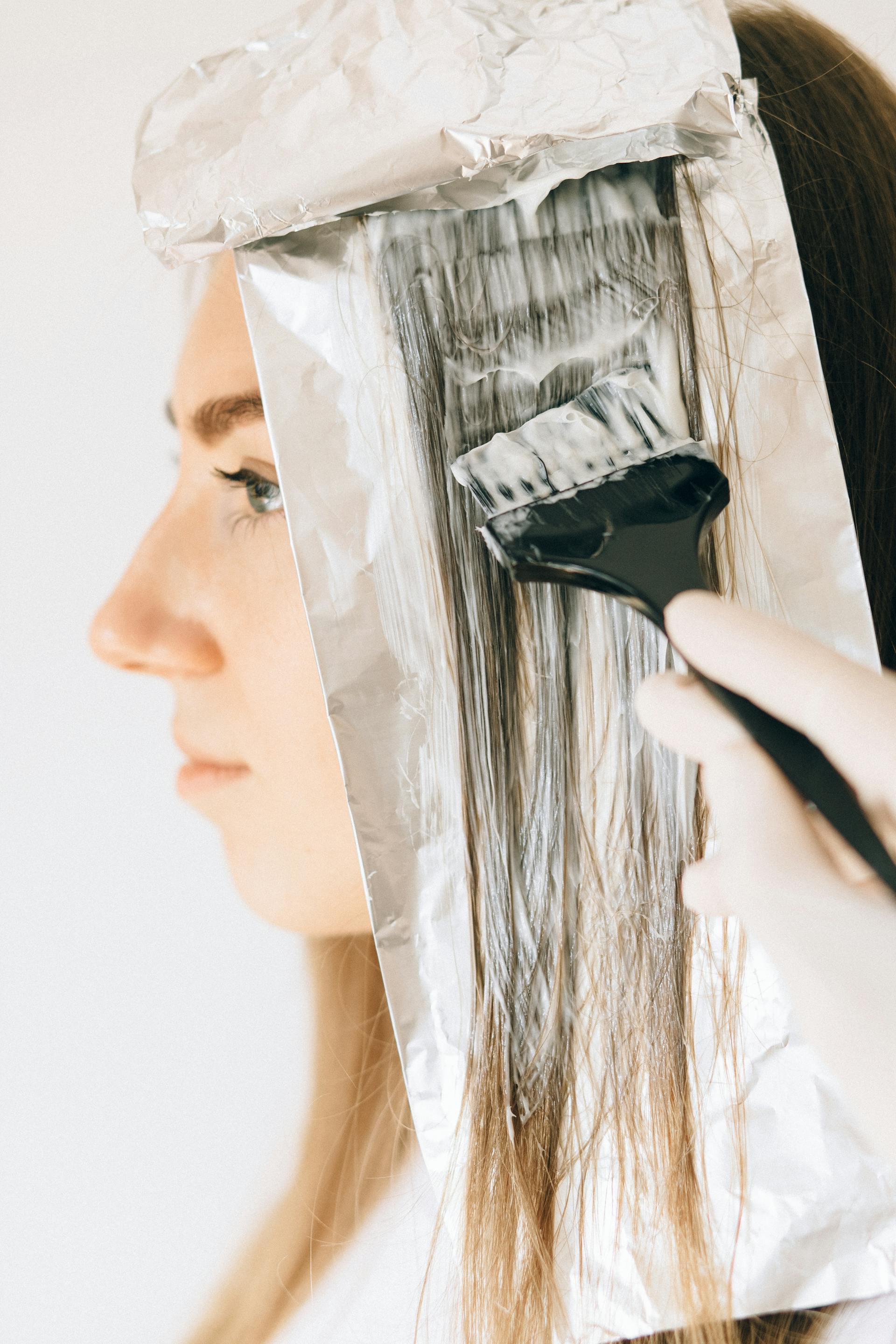 Mains de la coloriste appliquant un balayage